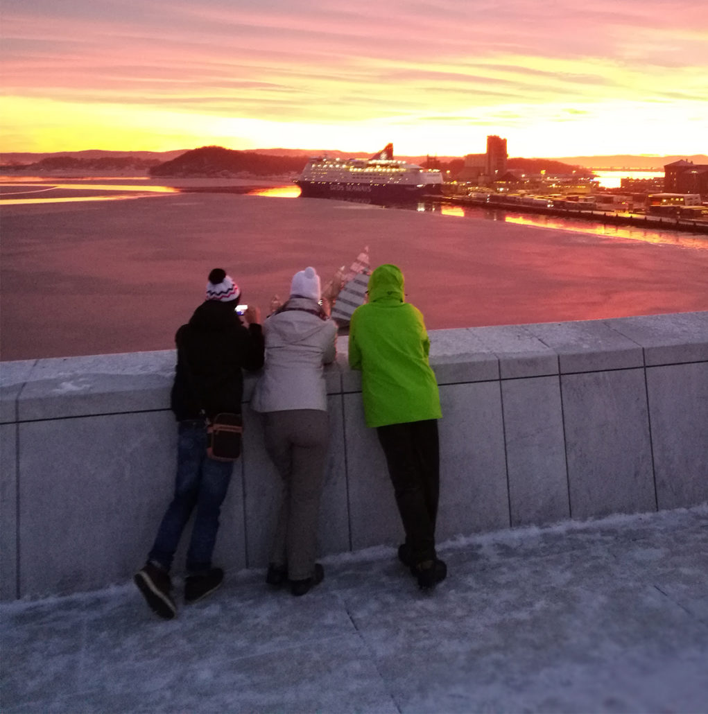 Tre mennesker ser på solnedgang fra Operataket